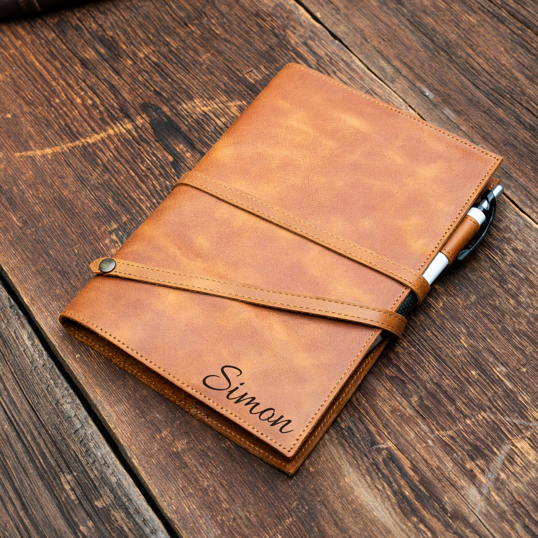 Tan leather journal engraved with the name Simon, with a pen